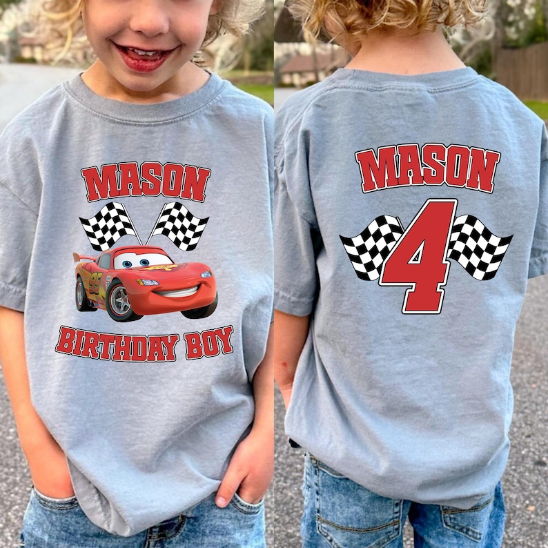 A young child wearing a gray t-shirt with a personalized design featuring a red race car and the name "Mason" printed on it.