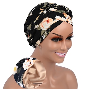 May include: Black floral print head wrap with cream and peach-colored roses. The head covering has a satin lining. The head wrap is designed to be worn on the head.