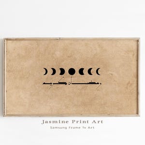 Op de afbeelding: Een rechthoekige ingelijste print met een bruinachtige achtergrond, met zwarte maanfase-illustraties en Arabisch schrift. De print zit in een lichtgekleurde lijst. De tekst "Jasmine Print Art" en "Samsung Frame Tv Art" staat onderaan.