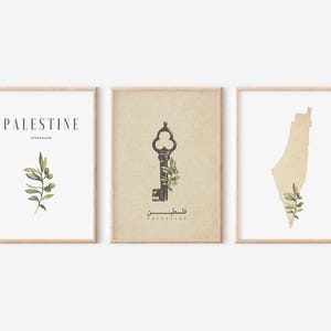 May include: Three framed art prints with a neutral color palette. The prints feature the word "PALESTINE" with "JERUSALEM" below, a vintage key, and a map outline, all with olive branch accents. The frames are a light wood color.