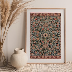 Op de afbeelding: Een ingelijste print van een vintage tapijt met een bloemenpatroon in tinten rood, groen en blauw. Het tapijt is omgeven door een rode rand.