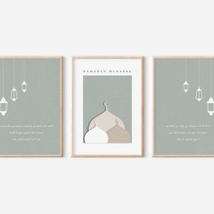 May include: Three printable wall art prints with a sage green background. The center print features a mosque with a white dome and a brown dome. The text "RAMADAN MUBARAK" is at the top of the print. The left and right prints feature white lanterns hanging from the ceiling. Arabic text is on each print.