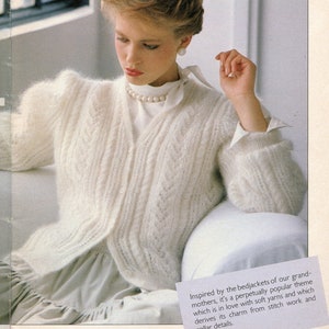 Peut inclure: Page de magazine vintage avec une femme portant un cardigan blanc texturé à col en V et fermeture boutonnée. Le texte en haut indique "THE FEMININE STITCH". Le cardigan présente un motif délicat.