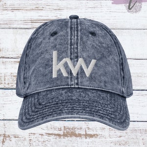 May include: A blue denim baseball cap with a white embroidered "KW" logo. The cap has a distressed look and a curved brim.