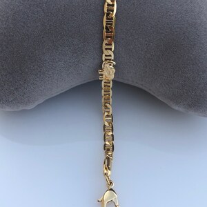 Peut inclure: Un bracelet cha&icirc;ne de couleur or avec un fermoir mousqueton. Le bracelet pr&eacute;sente une s&eacute;rie de maillons de cha&icirc;ne imbriqu&eacute;s. Un petit charm en forme d'&eacute;l&eacute;phant est attach&eacute; &agrave; la cha&icirc;ne.