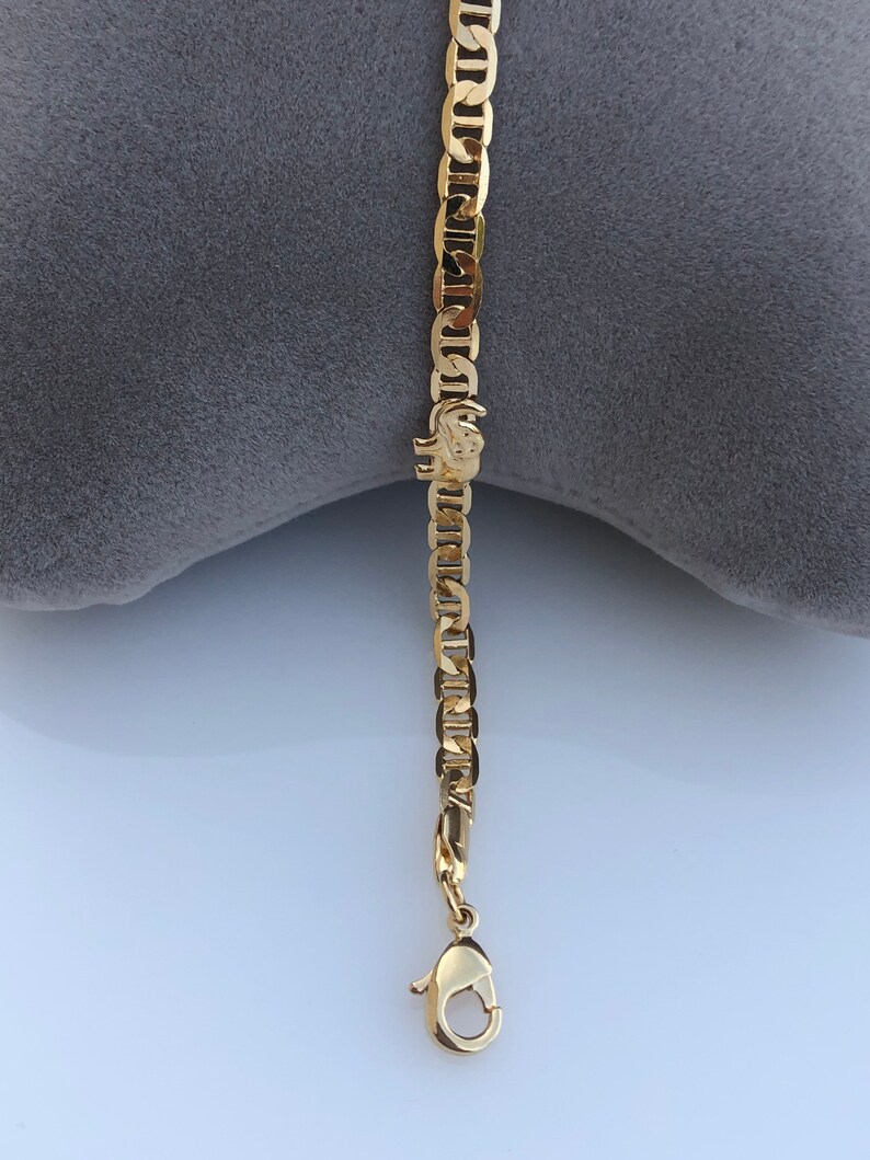 Peut inclure: Un bracelet cha&icirc;ne de couleur or avec un fermoir mousqueton. Le bracelet pr&eacute;sente une s&eacute;rie de maillons de cha&icirc;ne imbriqu&eacute;s. Un petit charm en forme d'&eacute;l&eacute;phant est attach&eacute; &agrave; la cha&icirc;ne.