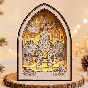 Può includere: Una scatola luminosa in legno ad arco con una scena natalizia a strati che mostra un albero centrale, Babbo Natale su una slitta e due bambini che si scambiano un regalo. Il design include bancarelle con le scritte GIFTS e TREATS e un orso.
