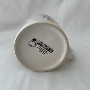 May include: White ceramic mug with a handle. The bottom of the mug features the text "SOUTHEAST" in a black rectangle, along with a palm tree and mug graphic. The mug is marked "MADE IN KOREA".