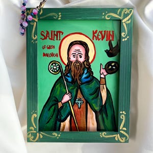 May include: A green wooden frame with gold accents surrounds a painting of Saint Kevin of Glen Daloch. The painting depicts Saint Kevin holding a staff and a bird in his hand. The background is green with a yellow halo around Saint Kevin's head.