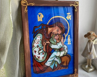 May include: A framed painting of a religious icon depicting the Virgin Mary holding a baby Jesus. The icon is painted in a traditional style with gold accents and a blue background. The frame is made of wood and has a gold trim.
