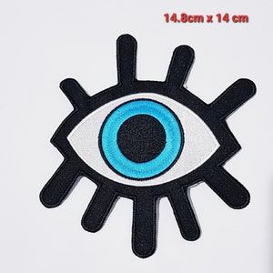 Puede incluir: Un parche para el ojo negro y blanco con un ojo azul en el centro. El parche para el ojo mide 14,8 cm por 14 cm.