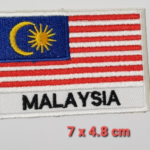 Può includere: Toppa ricamata con la bandiera della Malesia. Il design include un cantone blu con una mezzaluna e una stella gialle e strisce rosse e bianche. La parola "MALAYSIA" è ricamata in nero. La toppa misura 7 x 4,8 cm.
