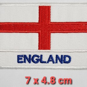 May include: White embroidered patch with a red cross and the word "ENGLAND" in blue lettering. The patch measures 7 cm by 4.8 cm.