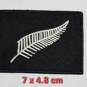 May include: Black embroidered patch with a white fern design. The patch measures 7 x 4.8 cm.