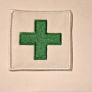 Peut inclure: Un patch carré blanc avec une croix verte brodée au centre.