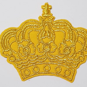 May include: A gold embroidered crown patch. The crown is detailed with intricate stitching and has a pointed top.