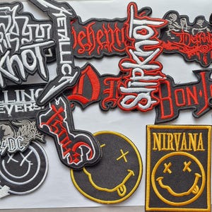 May include: A collection of embroidered fabric patches featuring various band logos and designs, including Slipknot, Metallica, Falling in Reverse, AC/DC, Bon Jovi, Nirvana, and Bring Me The Horizon, rendered in black, white, red, and yellow thread.