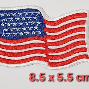 May include: A red, white and blue American flag patch with 50 white stars on a blue field. The flag is waving in the wind and has a white border. The patch measures 8.5 x 5.5 cm.