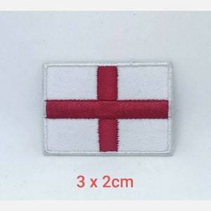 Puede incluir: Parche blanco bordado con una cruz roja, que representa la bandera de Inglaterra. El parche mide 3 cm por 2 cm.