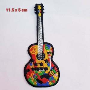 May include: A colourful embroidered patch of a guitar with peace signs, stars, and the word "LOVE" on the body. The guitar is 11.5 cm by 5 cm.