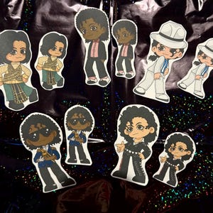 Könnte beinhalten: Eine Sammlung von Cartoon-Aufklebern mit einem Popstar in verschiedenen Outfits. Die Aufkleber zeigen den Sänger in verschiedenen Posen, mit einem weißen Anzug und Fedora, einem schwarzen Outfit und anderen farbenfrohen Ensembles. Die Aufkleber befinden sich auf einem glänzenden, dunklen Hintergrund.