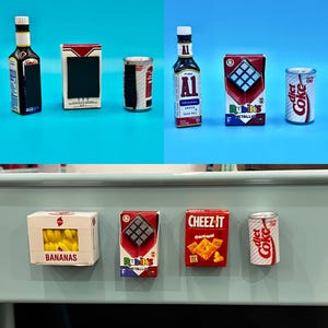 May include: Miniature food items including a bottle of A1 sauce, a Rubik's cube box, a can of Diet Coke, a box of bananas, and a box of Cheez-Its. The items are arranged on a blue surface.