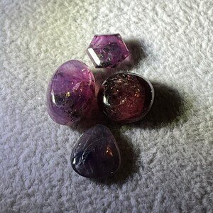 Könnte beinhalten: Vier violette Edelsteine, einer hat eine sechseckige Form, die anderen drei sind abgerundet.