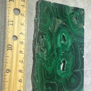May include: A green malachite stone with a swirling pattern. The stone is about 4 inches long and 3 inches wide.