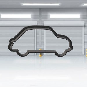 May include: A black car outline is positioned centrally in a bright, white garage. The car shape is basic, with a curved roof and a flat base. The garage features white walls, roller shutter doors, and yellow and black striped bollards.