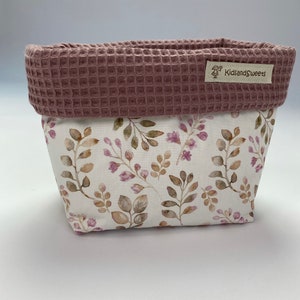 May include: A pink and white fabric storage basket with a floral pattern and a waffle-textured top. The basket has a label that says "KidsandSweets".