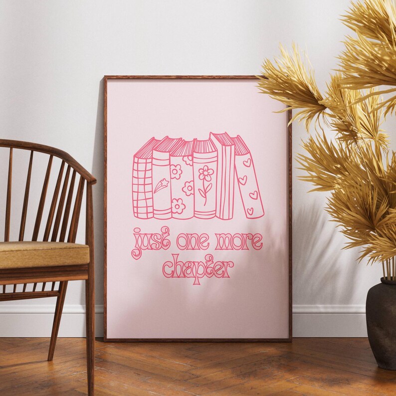 May include: Pink framed print with a stack of books and the text "just one more chapter" in a pink script font.