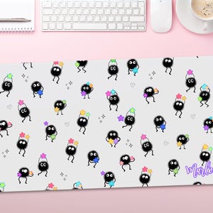 May include: A white mouse mat with a repeating pattern of black cartoon characters holding colourful stars. The text "Marlen" is in the bottom right corner of the mouse mat.