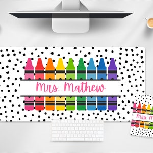 May include: A white desk mat with black polka dots and a row of colorful crayons. The mat has a banner with the text "Mrs. Mathew". A matching mouse pad with the text "Mrs. Math" is also shown.