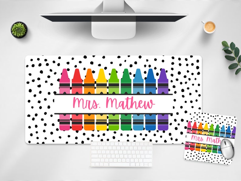 May include: A white desk mat with black polka dots and a row of colorful crayons. The mat has a banner with the text "Mrs. Mathew". A matching mouse pad with the text "Mrs. Math" is also shown.