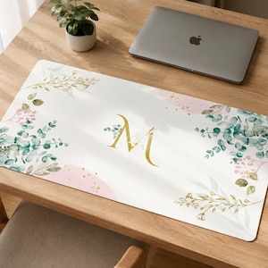 Peut inclure: Un tapis de bureau rectangulaire à fond blanc orné d'une lettre M dorée au centre, entourée d'illustrations à l'aquarelle de feuilles d'eucalyptus vertes, de petits bouquets de fleurs roses et d'accents botaniques dorés aux coins.
