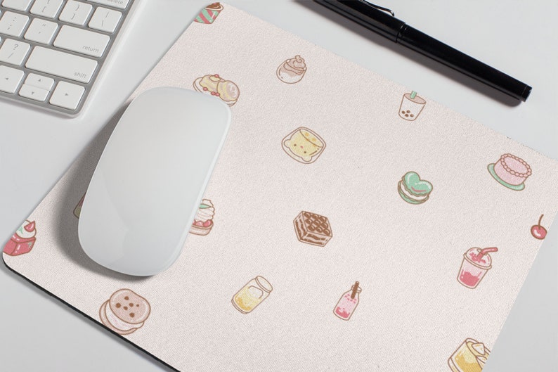May include: A pink and white mouse pad with a repeating pattern of various desserts and drinks, including cupcakes, cakes, macarons, and boba tea.