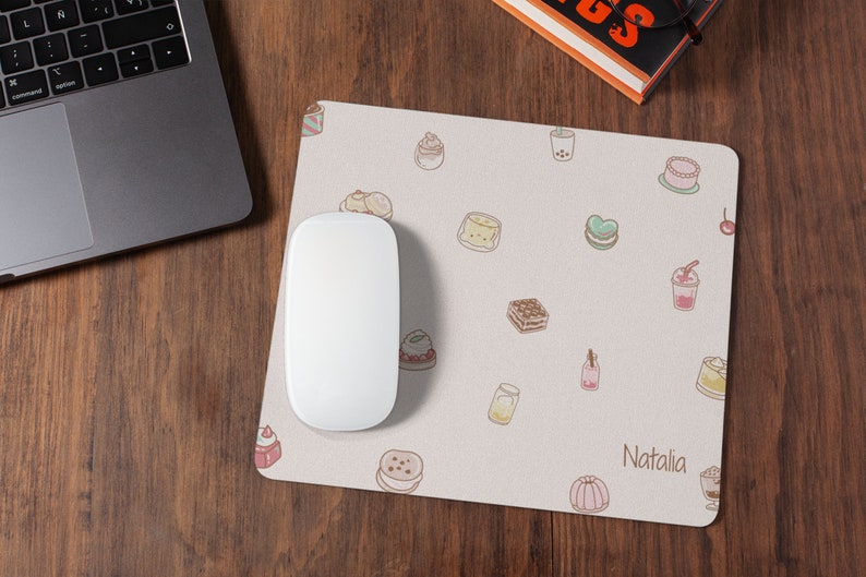 May include: A white mouse pad with a light pink background and a variety of colorful cartoon desserts and drinks. The text "Natalia" is printed in the bottom right corner.