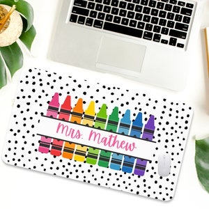 May include: A white mouse pad with black polka dots and a row of colorful crayons with the text "mrs. mathew" in pink.
