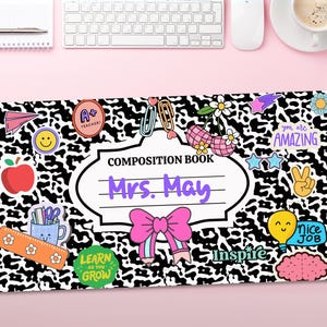 May include: Black and white composition book cover with a cow print pattern. The cover has a white label with the text "COMPOSITION BOOK" and "Mrs. May" in purple text. The cover is decorated with colourful stickers, including a red apple, a light blue pencil, a pink bow, and a yellow lightbulb.