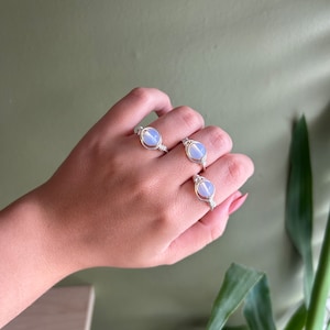 May include: Three silver wire wrapped rings with light blue oval shaped stones.