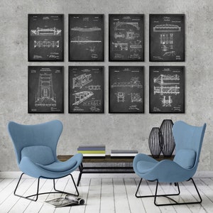 May include: Eight black and white framed prints of bridge designs. The prints are arranged in two rows of four, and are hanging on a gray wall. The prints are in a living room setting with two blue armchairs and a coffee table.