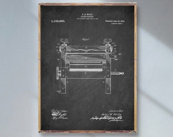 May include: A vintage black and white patent drawing of a clothes wringer, with the patent number 1,100,850 and the date June 23, 1914. The drawing is framed and hanging on a white wall.