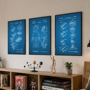 May include: Three rectangular wall art prints featuring white technical patent diagrams on a blue background. The prints are displayed in thin black frames, arranged horizontally on a light-colored wall above a long wooden storage unit.