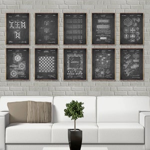May include: A set of nine vintage-style black and white prints of board game patents. The prints feature illustrations of classic games like checkers, Monopoly, and dice. Each print has a white border and is framed in a black frame.