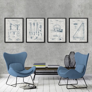 May include: Four vintage blueprint style prints of drafting tools, including a protractor, compass, and a T-ruler. The prints are framed in black and displayed on a grey wall above two blue armchairs.