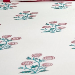 May include: White cotton bedding with a repeating pattern of pink and green floral designs.