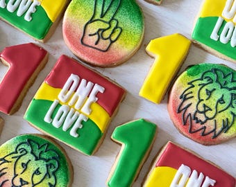 Op de afbeelding: Assortiment van gedecoreerde suikerkoekjes met een reggae-thema. De koekjes bevatten de woorden "One Love", vredestekens, leeuwen en het nummer één.