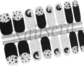 May include: Nail art stickers featuring a celestial design. The stickers have a black and white color scheme, with designs including stars, moons, and cat silhouettes. The stickers are arranged on a silver backing.