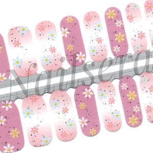 May include: Nail wraps with a floral pattern. The wraps have a pink base with white, yellow, and blue flower accents. The design includes a gradient effect and small black speckles.