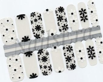 May include: A set of 10 white nail wraps with black and white daisy designs. The nail wraps are arranged in two rows of five.
